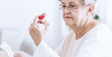 Older woman looking at a bottle of pills