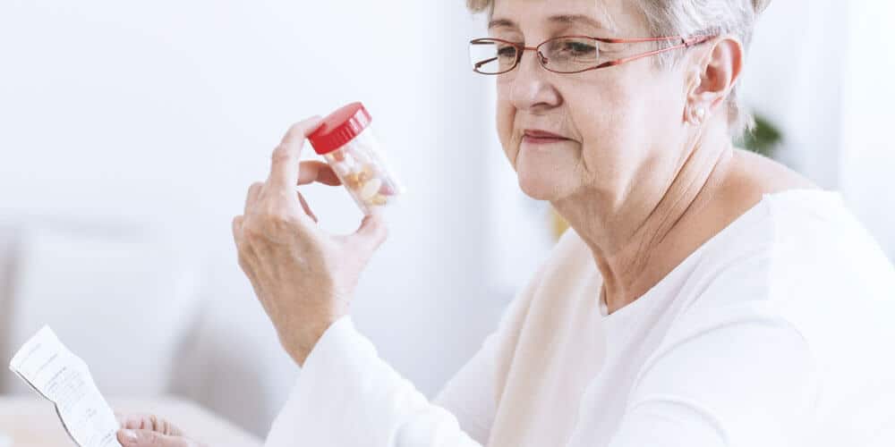 Older woman looking at a bottle of pills